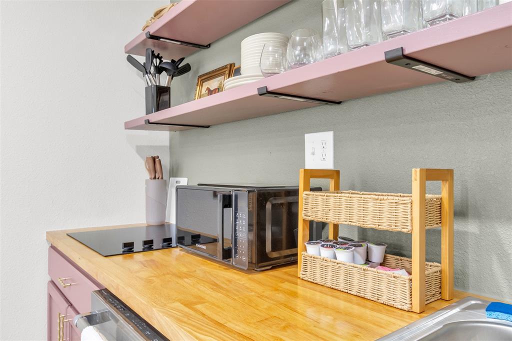 4121 Junius Street, Unit B Dallas, TX 75246 - Photo 26 of 32 Compact kitchen area featuring wood-finish countertops, an integrated cooktop, and open shelving