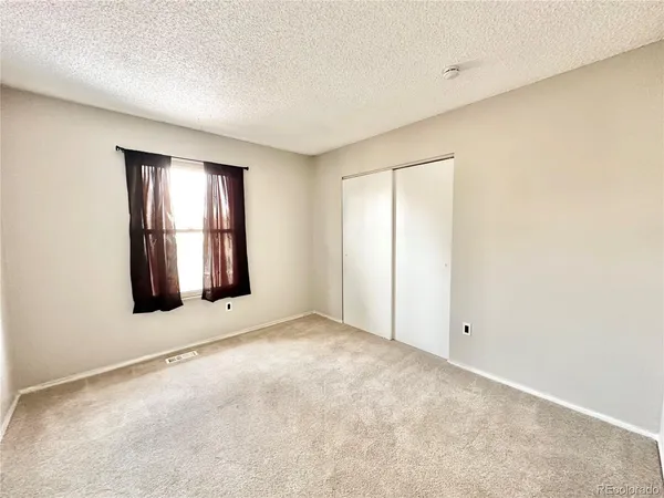 a view of an empty room with kitchen and a window