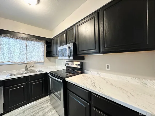 a kitchen with granite countertop a sink dishwasher microwave stove and cabinets