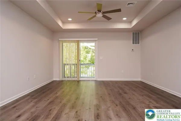 a view of an empty room with a window and wooden floor
