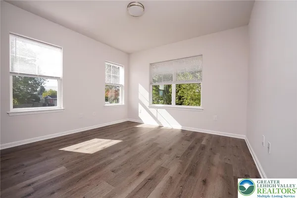 a view of an empty room with wooden floor and a window