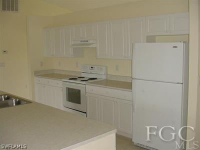 3111 35th Street Southwest Lehigh Acres, FL 33976 - Photo 3 of 10 a kitchen with a refrigerator stove and white cabinets