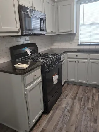 a kitchen with stainless steel appliances white cabinets granite counter tops and a wooden floor