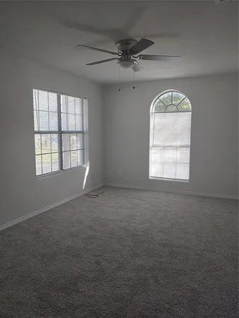 an empty room with windows and chandelier fan