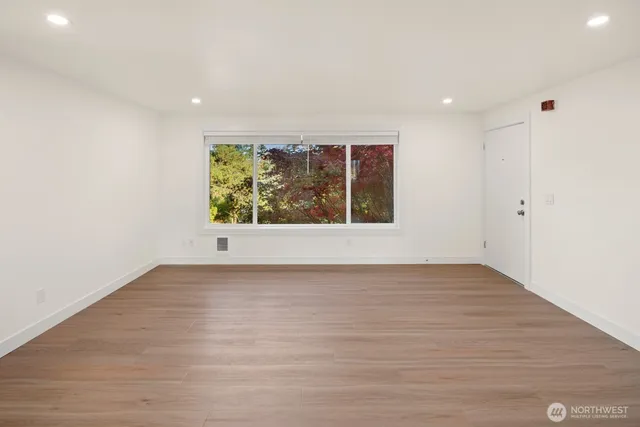 an empty room with wooden floor and window