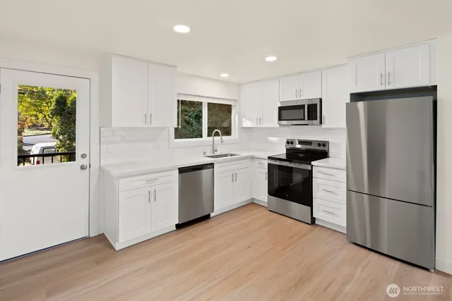 a kitchen with white cabinets stainless steel appliances and wooden floor