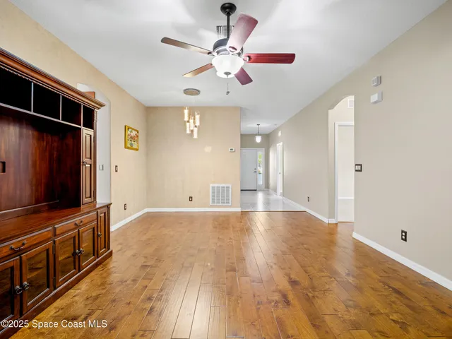 a view of an empty room with window and wooden floor