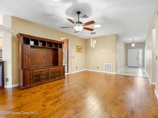 an empty room with a window and a chandelier fan