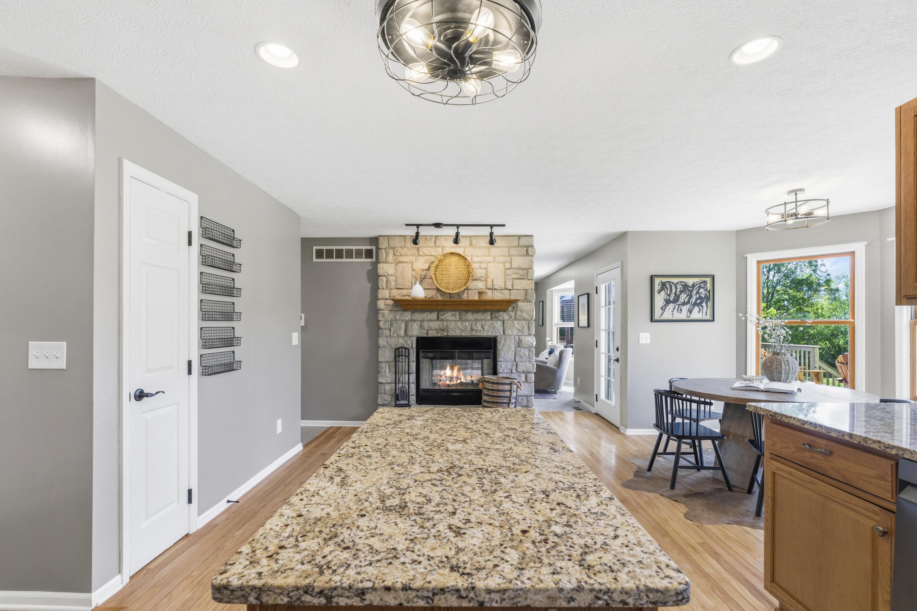8507 Benner Road Johnstown, OH 43031 - Photo 22 of 69 Large Kitchen with hardwood floors and Dining Area with bay window & double fireplace! Granite countertops, island, NEW Black Stainless Steel Appliances, including an induction oven! NEW Reverse Osmosis to sink/Fridge/Brio+