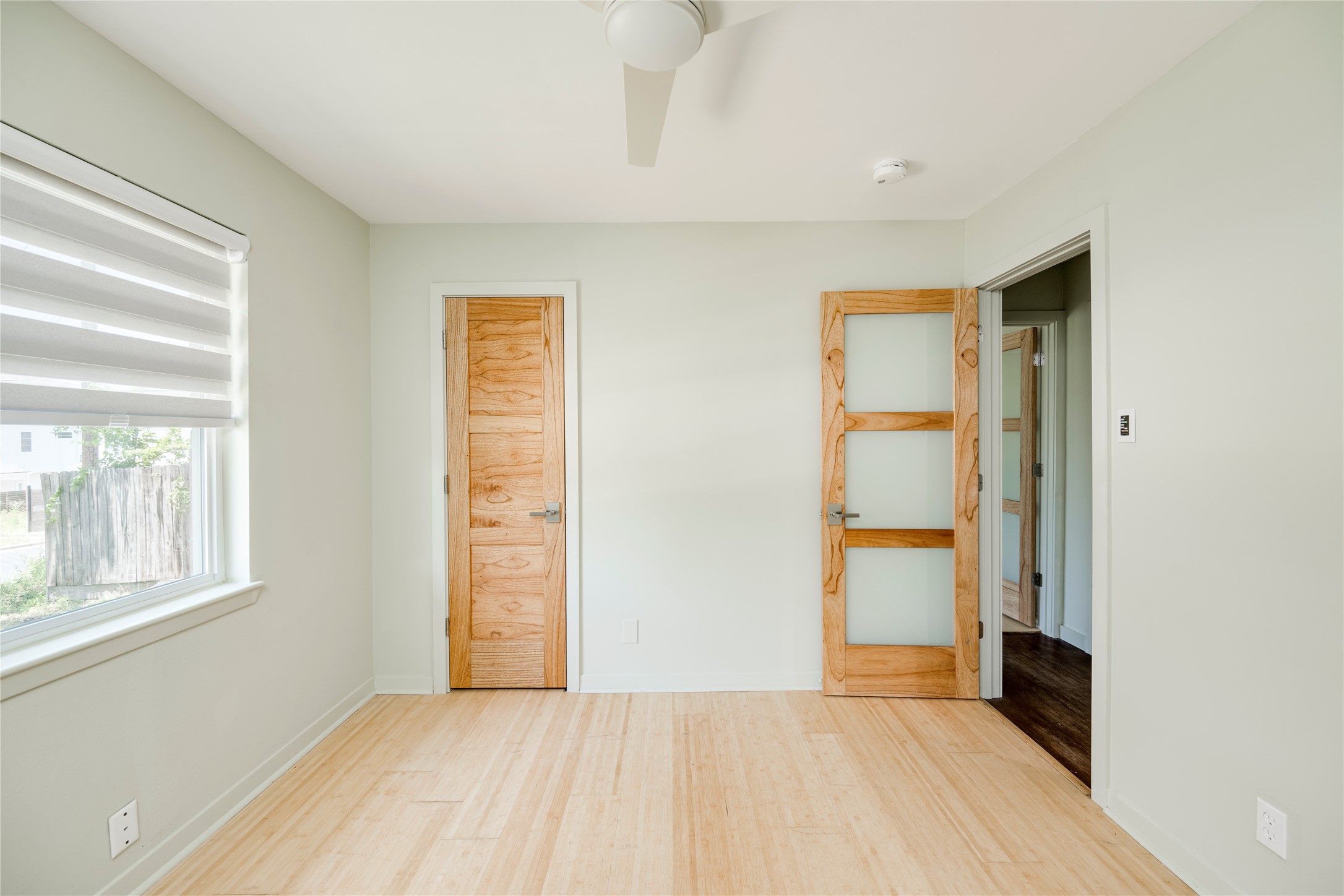 1707 Overhill Drive Austin, TX 78721 - Photo 18 of 36 Blonde wood floors extend throughout this bright bedroom, featuring modern doors and a cooling ceiling fan.