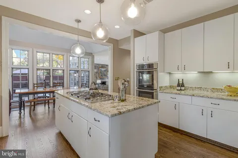 a kitchen with stainless steel appliances kitchen island granite countertop a table chairs and a refrigerator