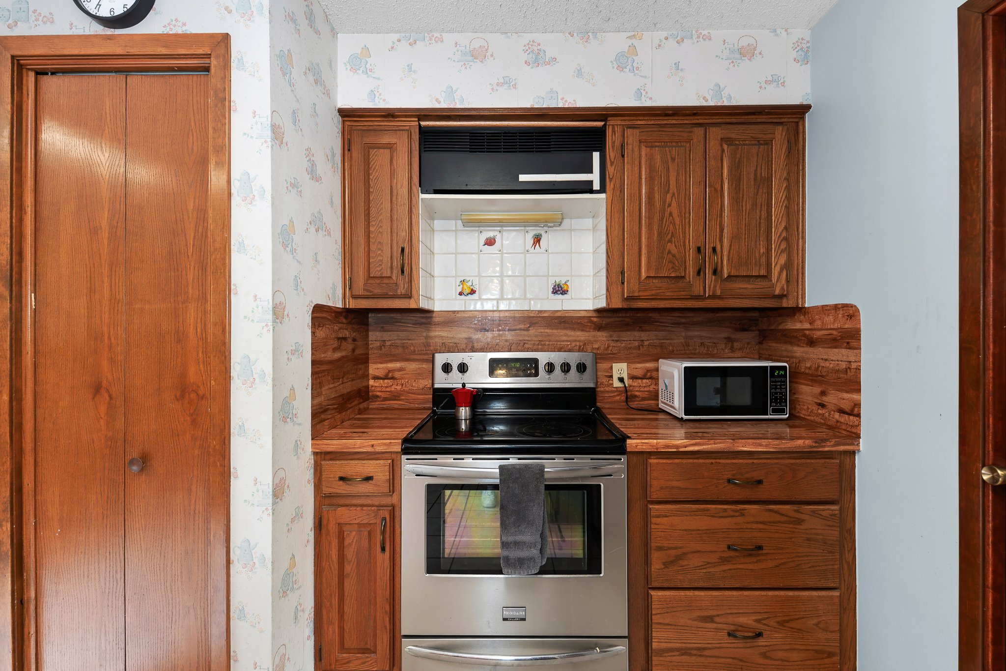 5600 Libyan Circle Austin, TX 78745 - Photo 15 of 37 Kitchen with electric stove, wallpapered walls, and wood finish cabinetry