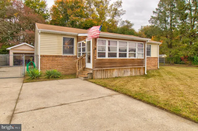 a view of house with backyard and trees in the background
