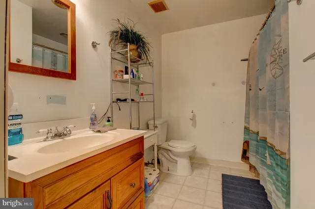 a view of a hallway with wooden floor and a bathroom