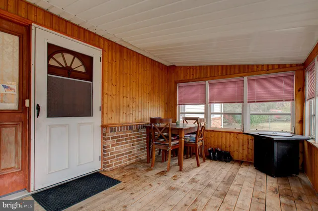 a view of a porch with wooden floor and front door