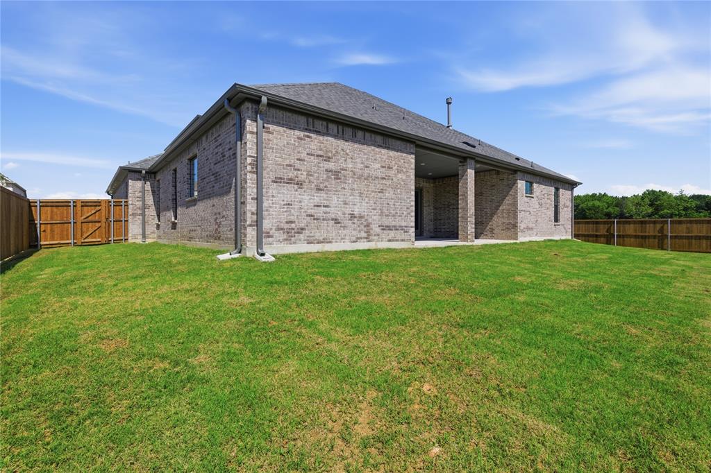 713 Anne Road Van Alstyne, TX 75495 - Photo 28 of 29 Expansive backyard featuring a manicured lawn, full privacy fencing, and a covered patio area