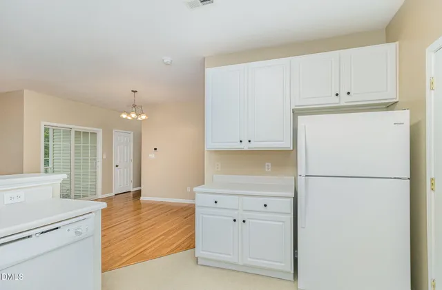 a view of a kitchen with refrigerator and wooden cabinets