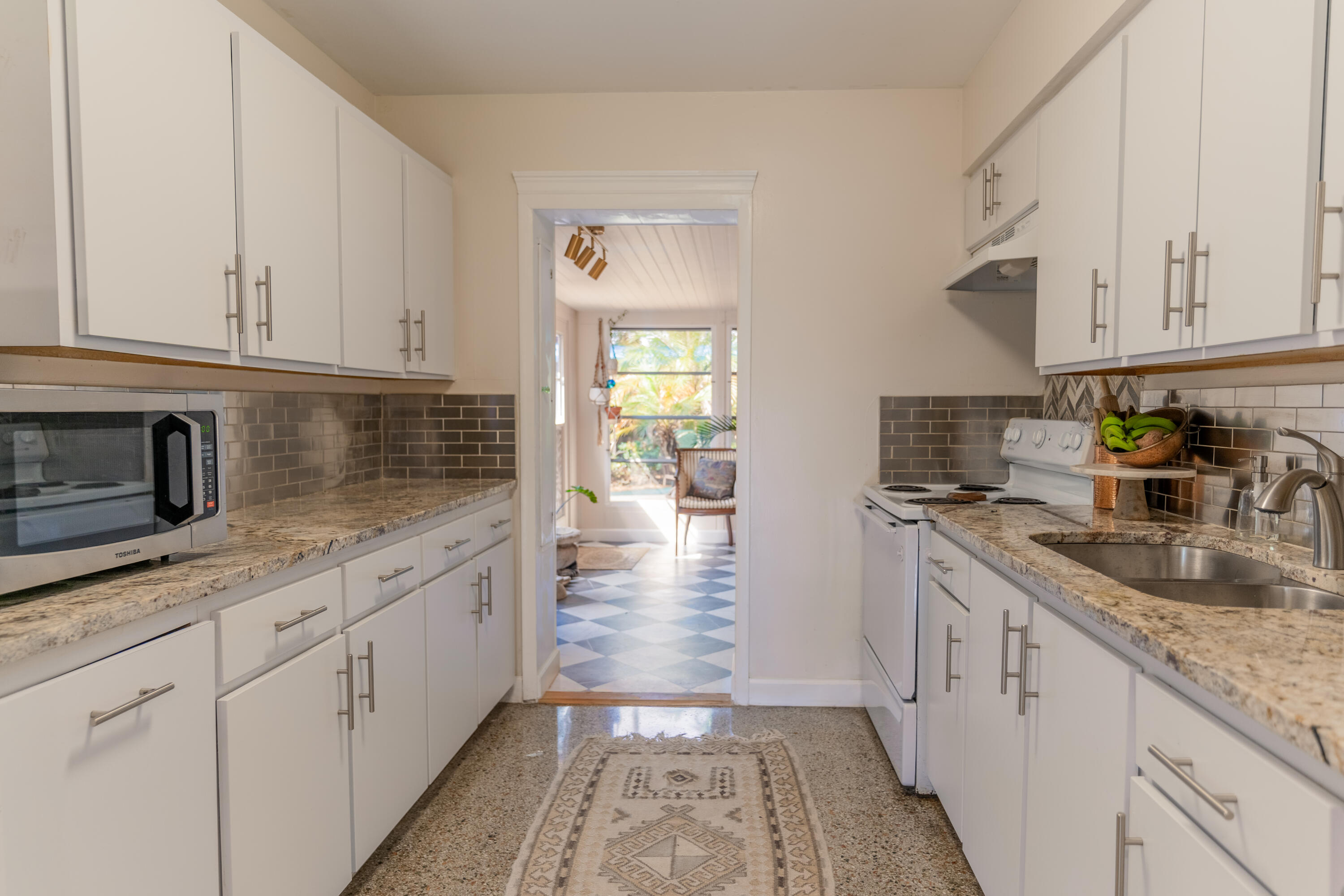 5155 Cleveland Road Delray Beach, FL 33484 - Photo 11 of 40 a kitchen with granite countertop a sink stainless steel appliances white cabinets and a window