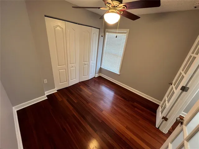 a view of an empty room with a ceiling fan and wooden floor