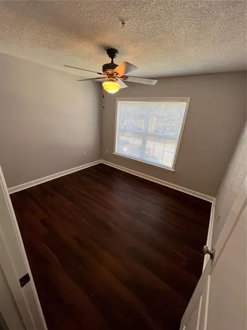 a view of an empty room with window and chandelier fan