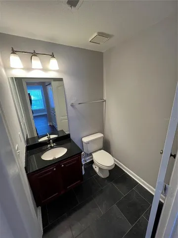 a bathroom with a granite countertop toilet a sink and a mirror