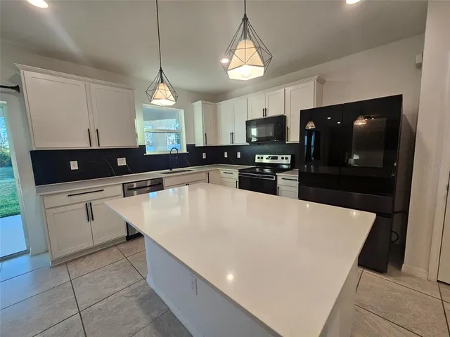 a large kitchen with granite countertop a stove a sink a counter top space and cabinets