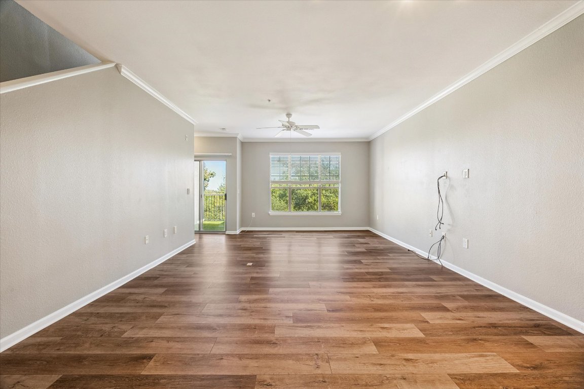 11203 Ranch Road 2222, Unit 1504 Austin, TX 78730 - Photo 2 of 10 Living room with crown molding, new flooring, and a ceiling fan