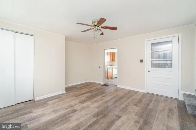 a view of empty room with wooden floor and ceiling fan