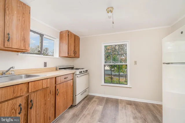 a kitchen with stainless steel appliances granite countertop a sink cabinets wooden floor and a window