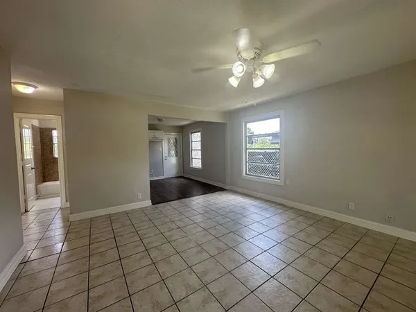 a view of an empty room with window and chandelier fan