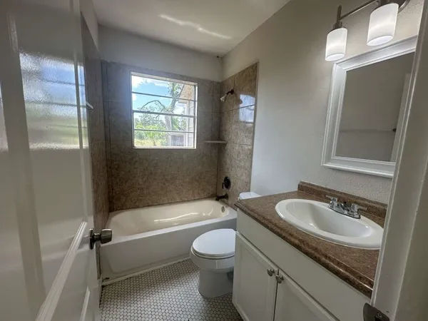 a bathroom with a granite countertop sink toilet a mirror and bathtub