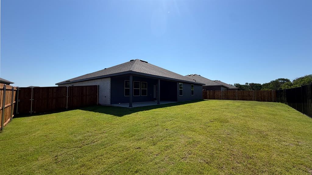 1913 Reveille Way Terrell, TX 75160 - Photo 30 of 35 Spacious backyard featuring a covered patio, expansive lawn, and surrounding wood fencing