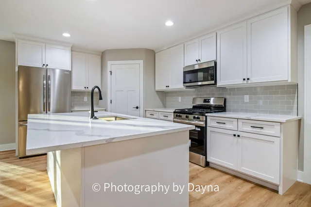 a kitchen with stainless steel appliances granite countertop a sink a stove a refrigerator and cabinets
