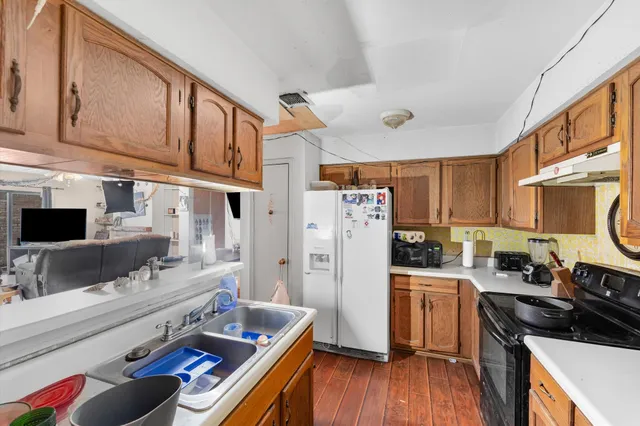 a kitchen with refrigerator a stove and wooden floor