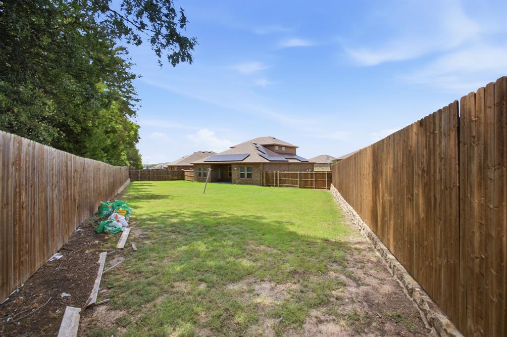 1328 Broaddus Road Forney, TX 75126 - Photo 31 of 31 Expansive backyard featuring a manicured lawn, full wood fencing, and a stone base