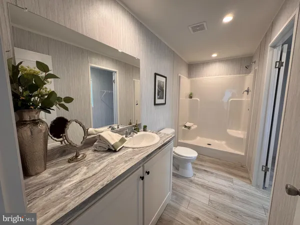 a bathroom with a granite countertop sink a toilet and shower