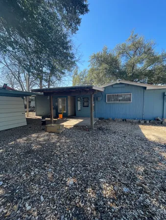 a view of a house with a yard and a large tree