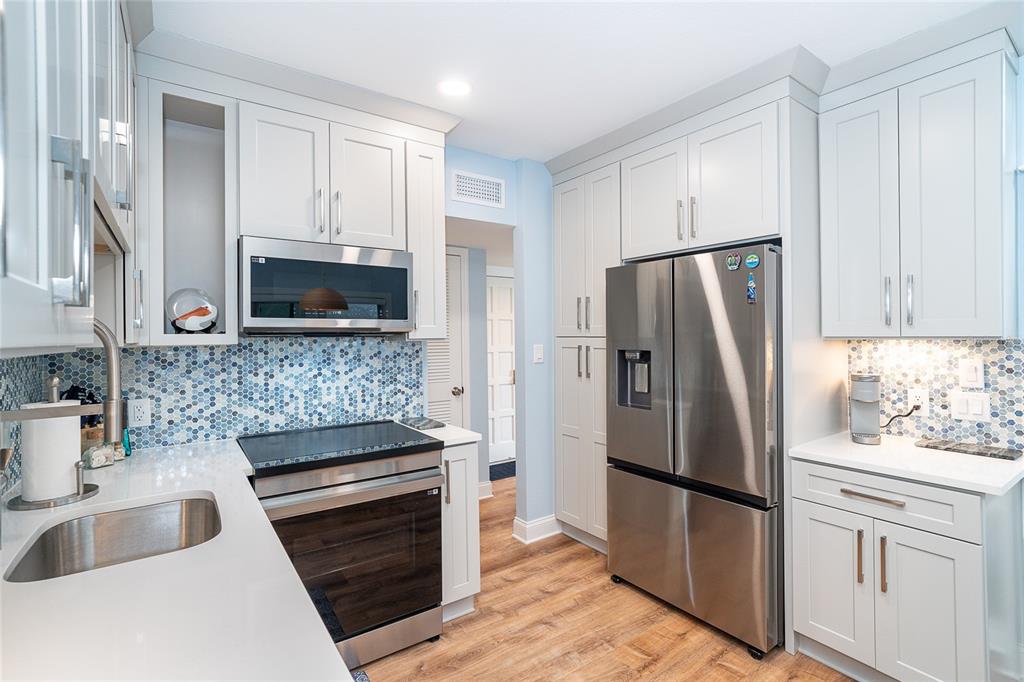 6005 North Beach Road, Unit 16 Englewood, FL 34223 - Photo 12 of 57 a kitchen with white cabinets and stainless steel appliances