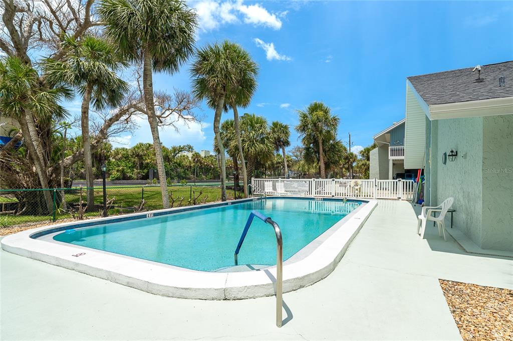 6005 North Beach Road, Unit 16 Englewood, FL 34223 - Photo 40 of 57 a view of a swimming pool with a lawn chairs under palm trees