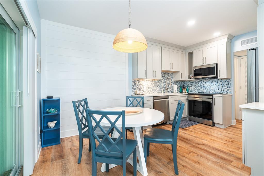 6005 North Beach Road, Unit 16 Englewood, FL 34223 - Photo 9 of 57 a kitchen with stainless steel appliances granite countertop a dining table chairs and a refrigerator