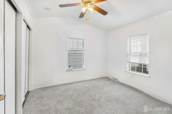 an empty room with windows and fan