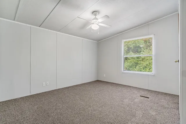 an empty room with windows and ceiling fan