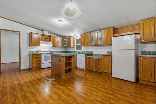 a kitchen with stainless steel appliances granite countertop a stove top oven a refrigerator a sink and a white cabinets