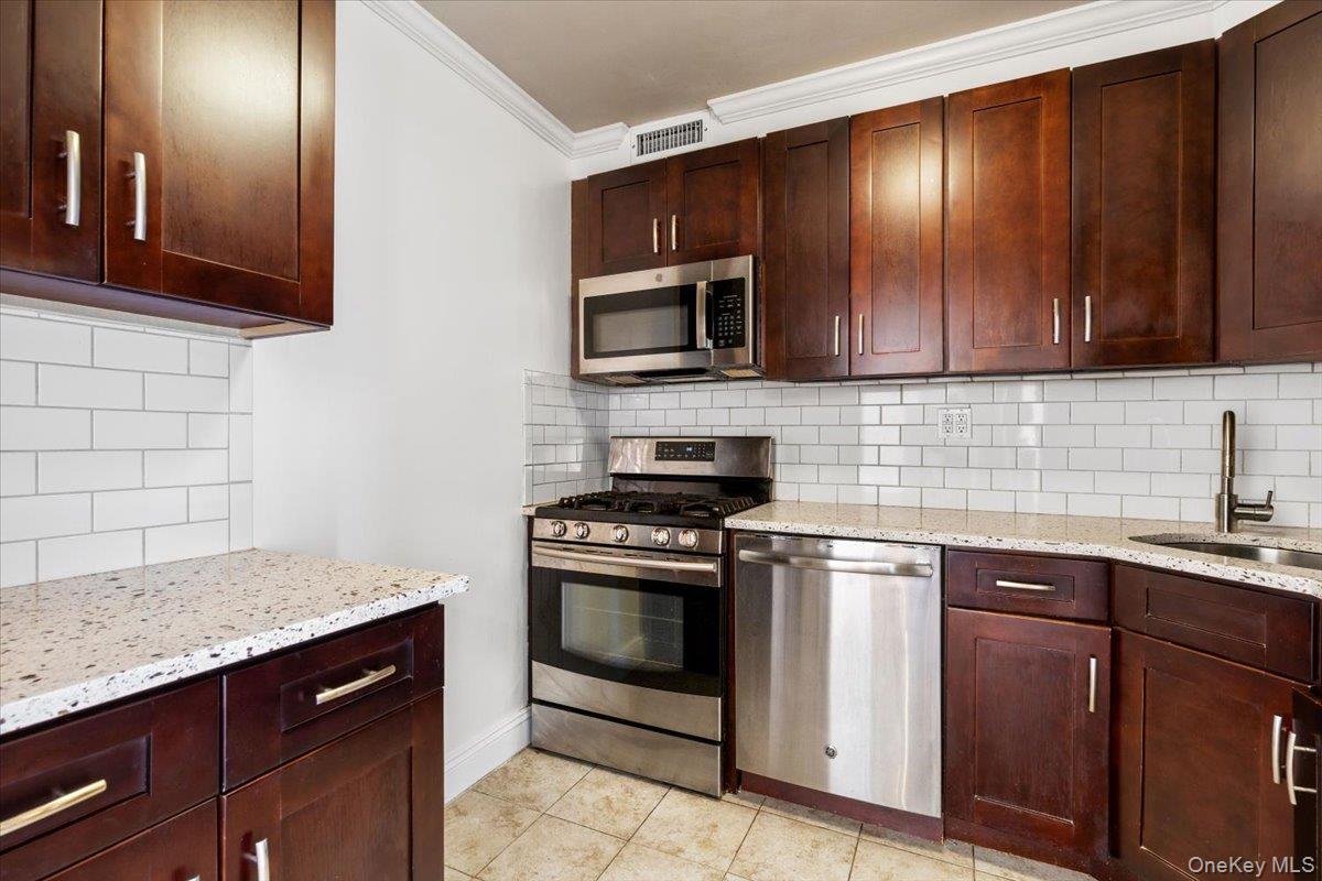 470 Halstead Avenue, Unit 5E Harrison, NY 10528 - Photo 6 of 22 a kitchen with granite countertop wooden cabinets and stainless steel appliances