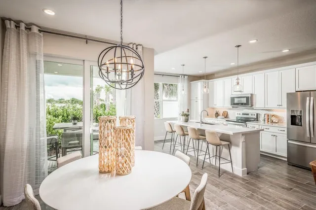 a kitchen with stainless steel appliances granite countertop a stove a refrigerator a dining table and chairs with wooden floor