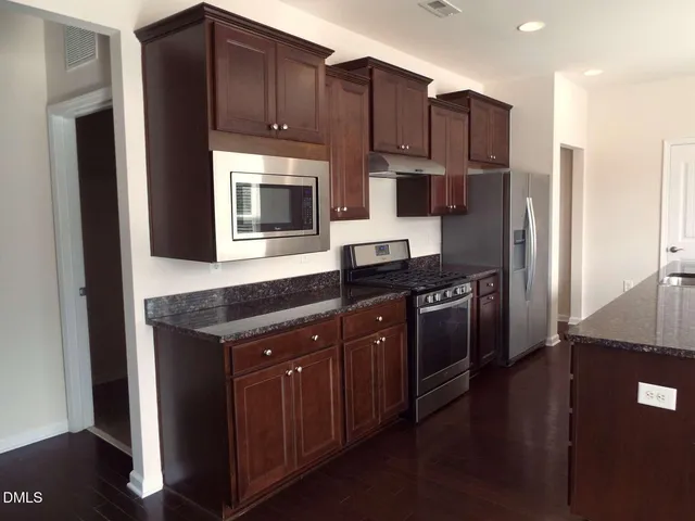 a kitchen with stainless steel appliances granite countertop a stove a refrigerator and a microwave