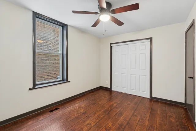 an empty room with wooden floor closet and ceiling fan