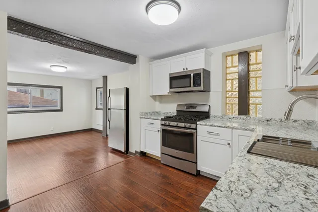 a kitchen with granite countertop a stove top oven and refrigerator