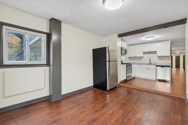 a view of kitchen with stainless steel appliances wooden floor and chair