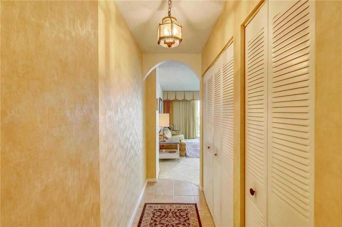 1505 North Riverside Drive, Unit 1208 Pompano Beach, FL 33062 - Photo 58 of 62 a view of a hallway with wooden floor and a chandelier
